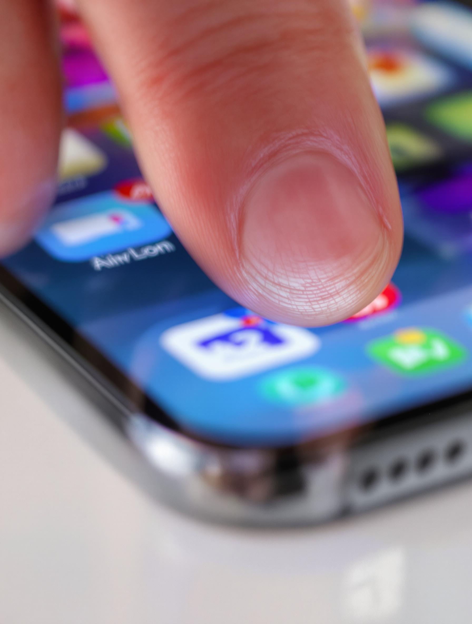 Doigt en appui long sur l’écran d’accueil de l’iPhone.
