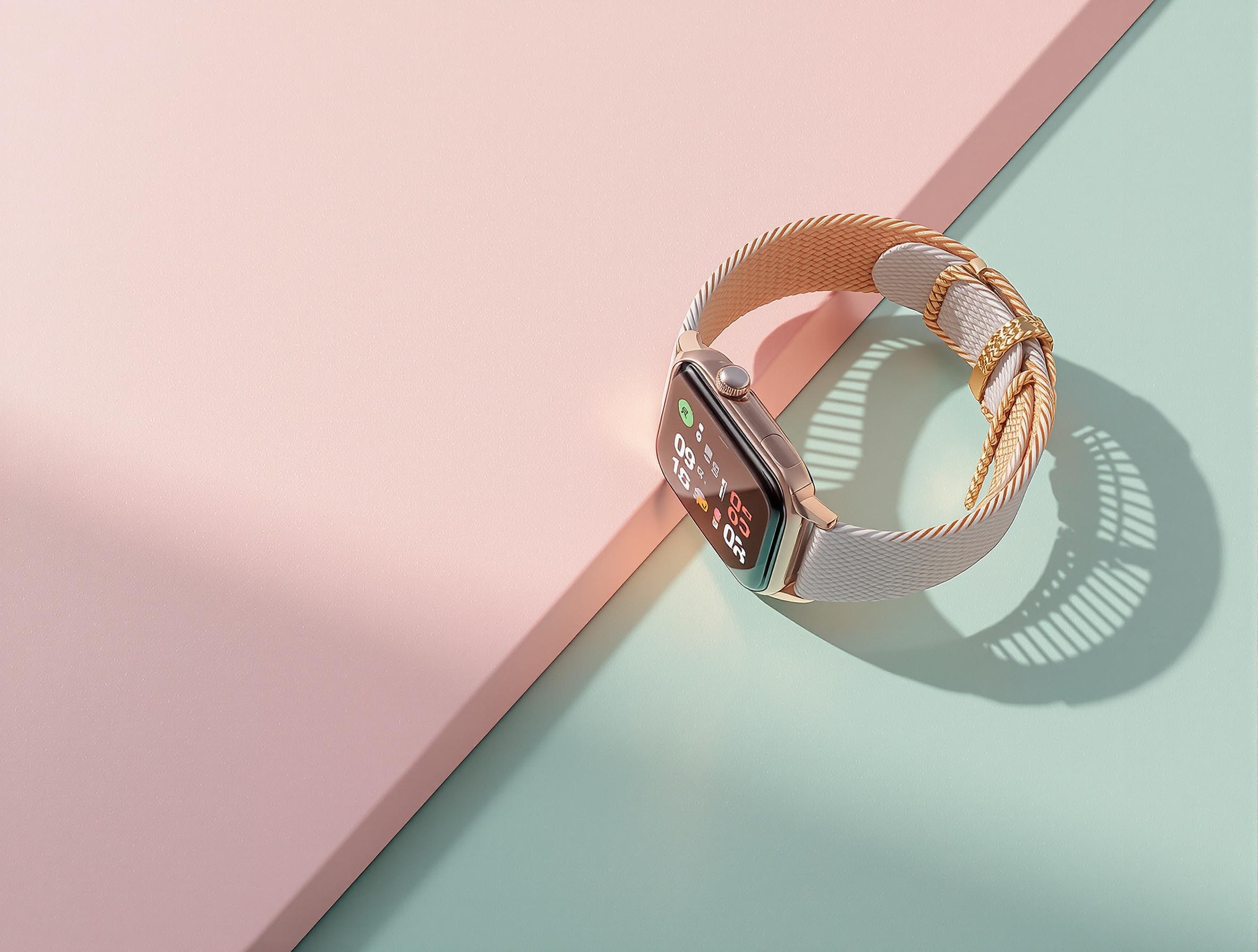 Montre connectée haut de gamme posée sur fond pastel rose quartz et vert menthe